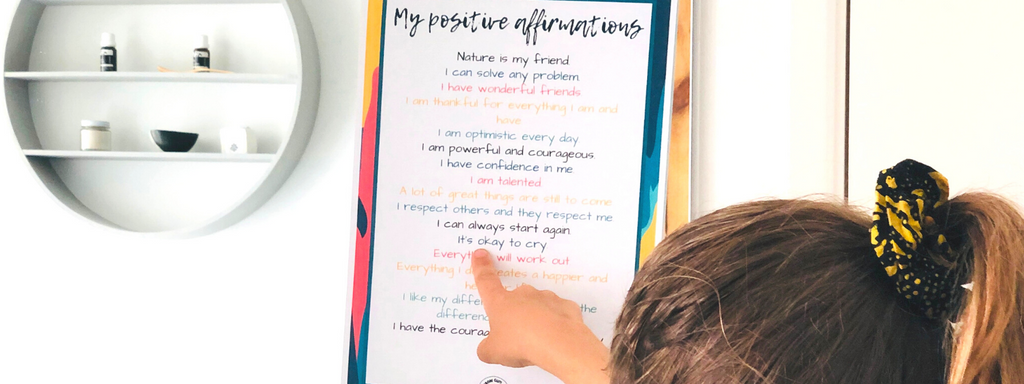 Girl pointing at a poster with self positive affirmations for kids to help build resilience and confidence